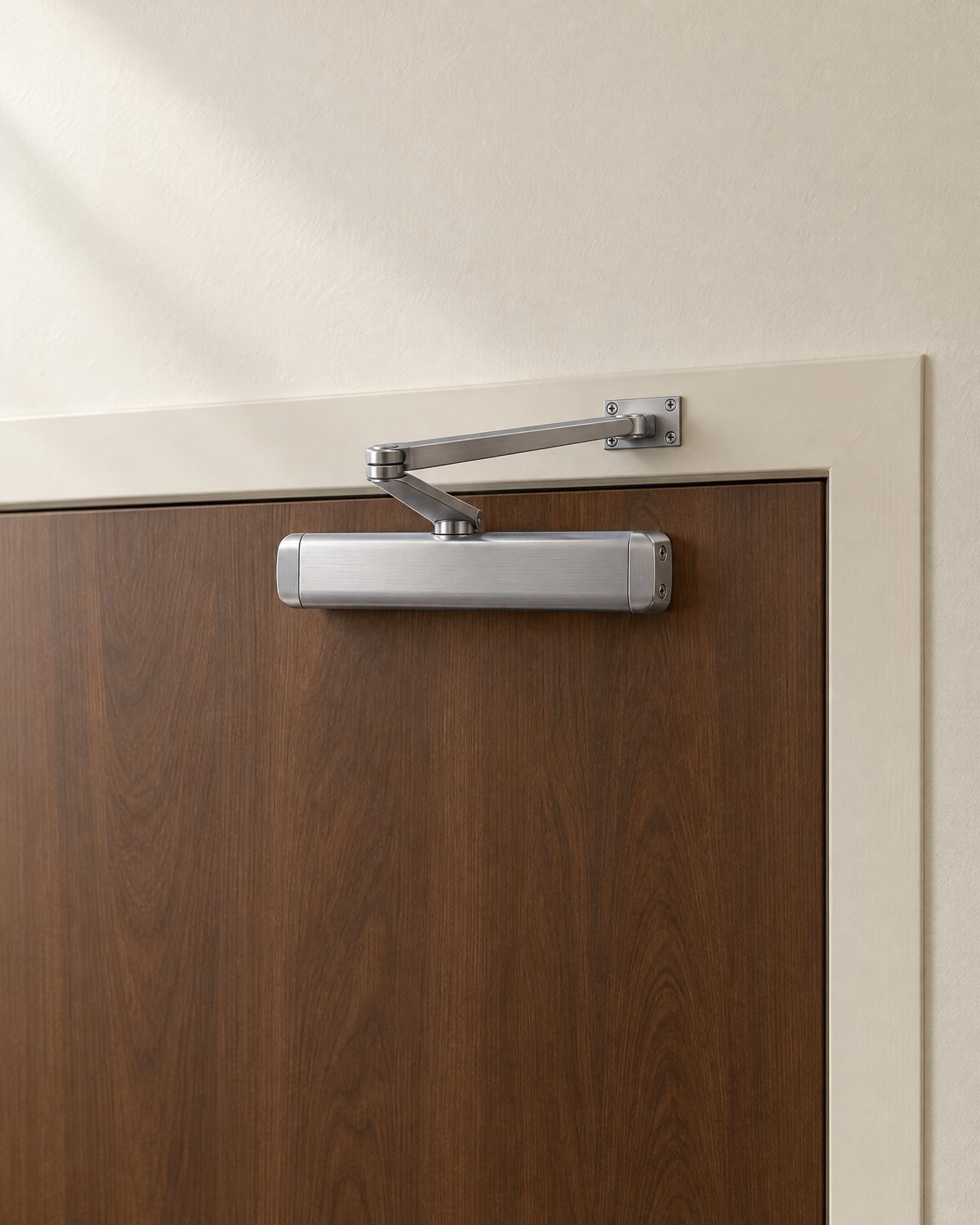 Illustration of an overhead door closer on a walnut door, with its two-part arm connected to a bracket on the door frame